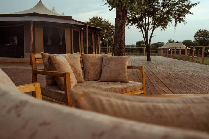 Comfortable outdoor lounge area on wooden deck of luxury tented safari camp.