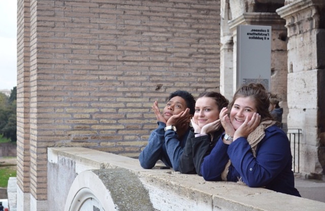 Trois personnes posant devant une structure historique en briques.