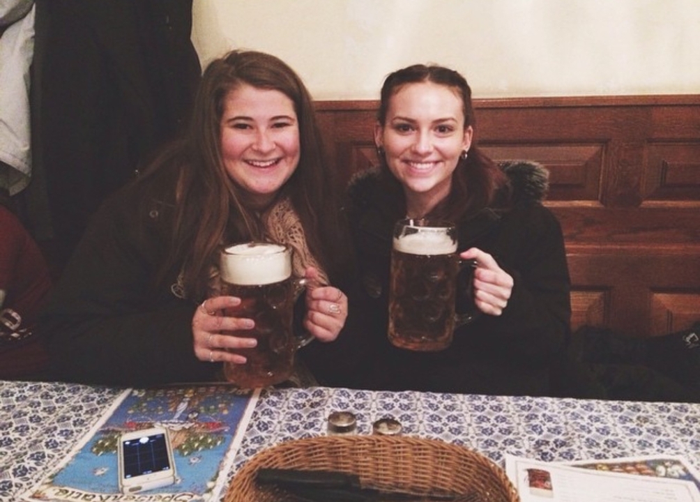 Deux amis dégustant de grandes chopes de bière à une table en bois.