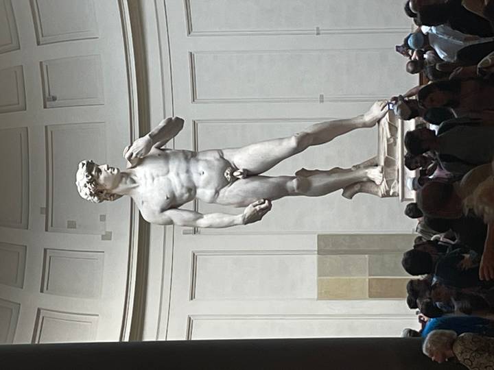 Michelangelo’s David stands majestically inside the Galleria dell’Accademia surrounded by visitors.