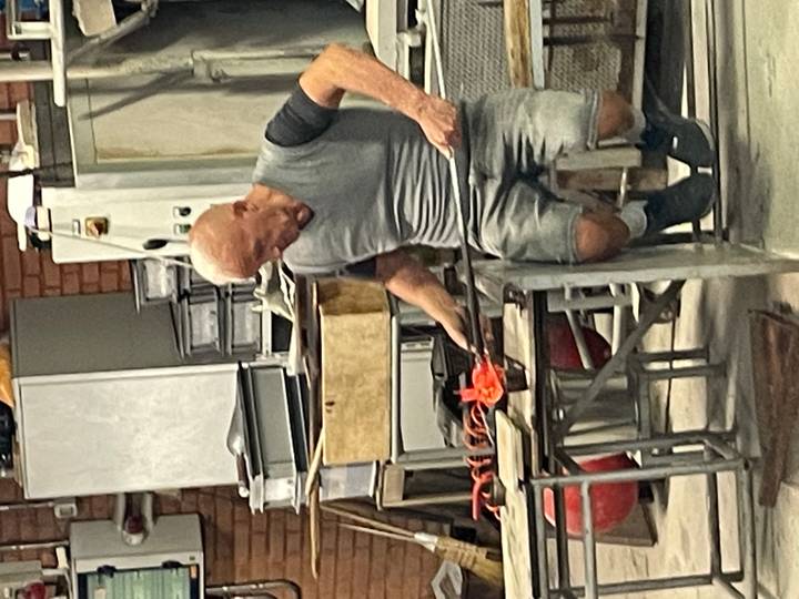 A glassblower shapes molten glass in an artisan workshop on Murano island.