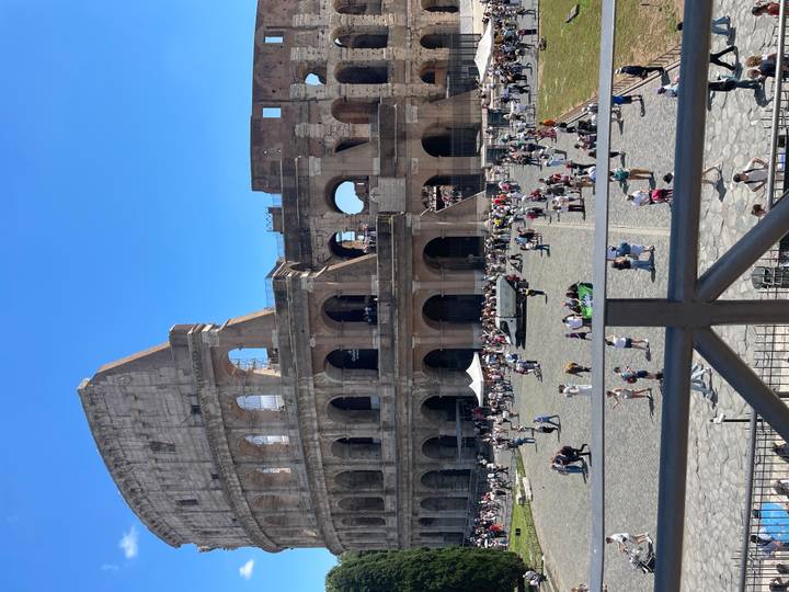 Crowds explore the interior tiers of the Colosseum on a bright summer day.