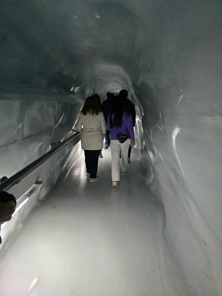 Visitors walk through an illuminated ice tunnel carved inside a glacier