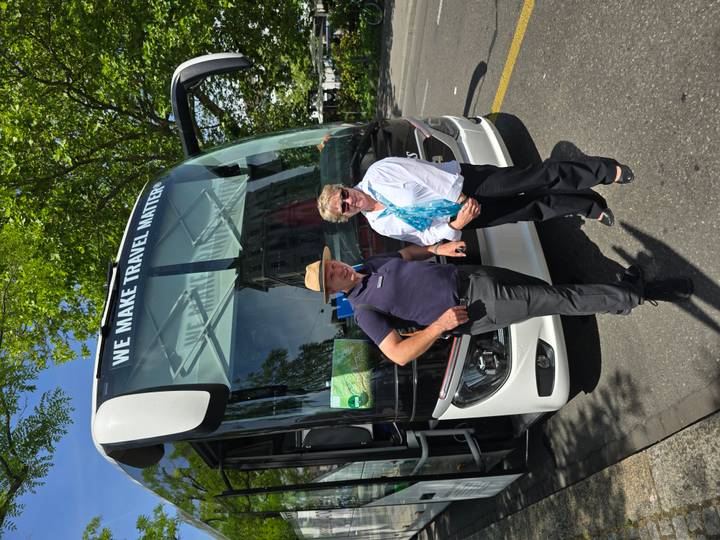 Coach driver and tour host posing in front of a modern white tour bus on a sunny day