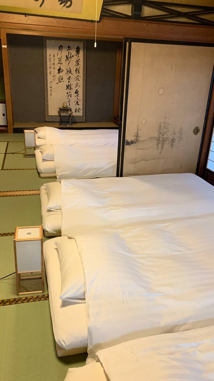 Traditional tatami room with neatly laid futon mattresses and white bedding in a Japanese ryokan