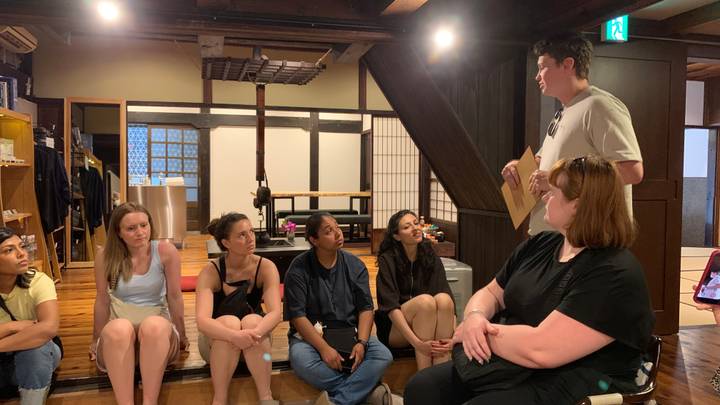 Small tour group listens to a briefing inside a traditional wooden interior with exposed beams