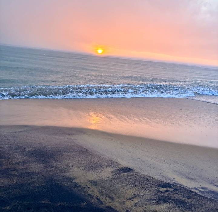 Serene sunset over gentle ocean waves washing a sandy beach.