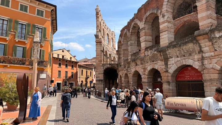 Roman amphitheatre in Verona bustling with sightseers and colorful surrounding buildings.