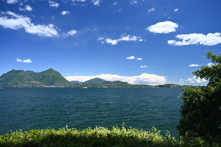 Wide expanse of deep blue lake under vibrant blue sky with scattered white clouds.