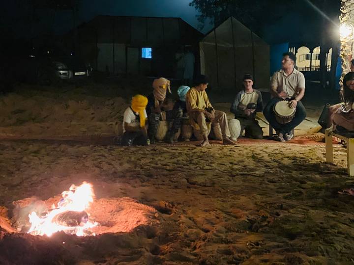 Night-time desert campfire with local musicians and tourists seated on carpets.