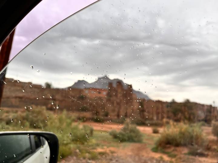 Raindrops on a car window with blurred scenery of desert cliffs in the background
