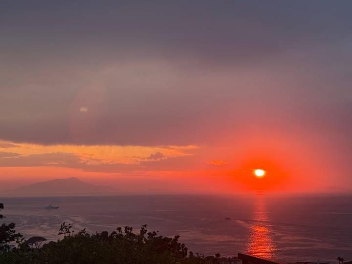 Brilliant orange sunset over the Tyrrhenian Sea with Mount Vesuvius silhouette