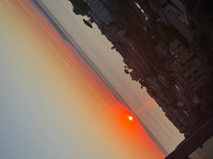 Sunset over the Mediterranean with coastal town rooftops in the foreground