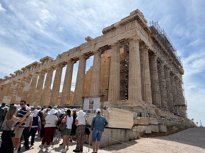 Crowd of tourists in front of the Parthenon’s massive columns under a partly cloudy sky