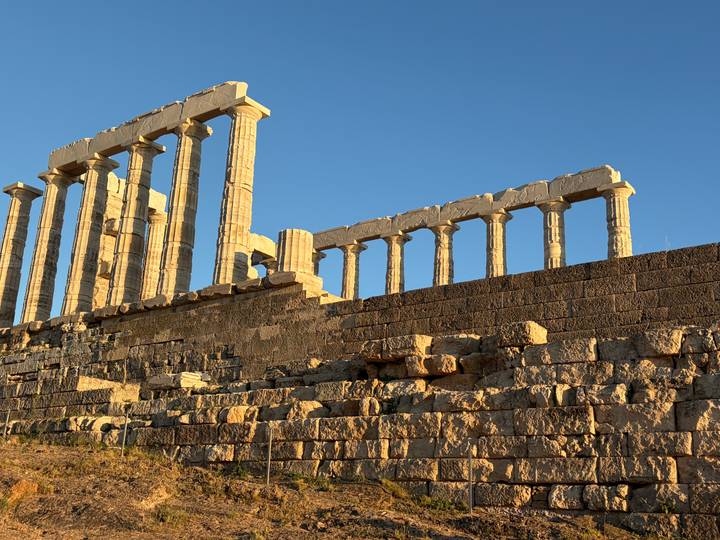 Sun-lit marble columns of the Temple of Poseidon towering above a rugged stone platform