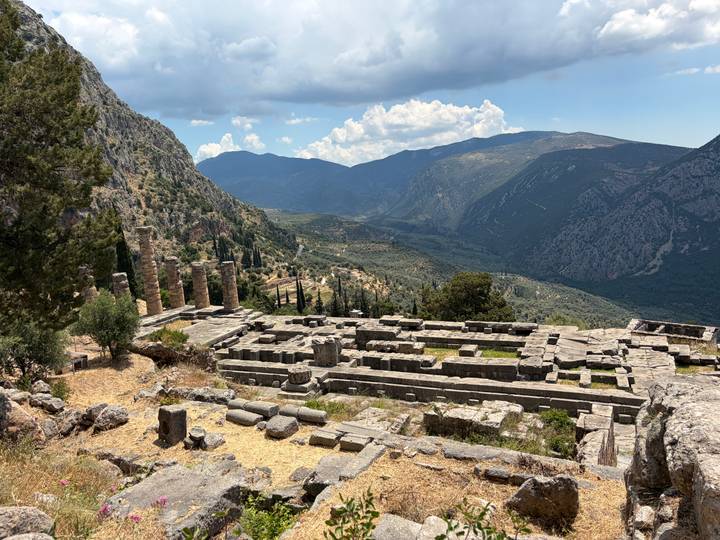 Ancient ruins of the Temple of Apollo in Delphi overlooking a dramatic mountain valley
