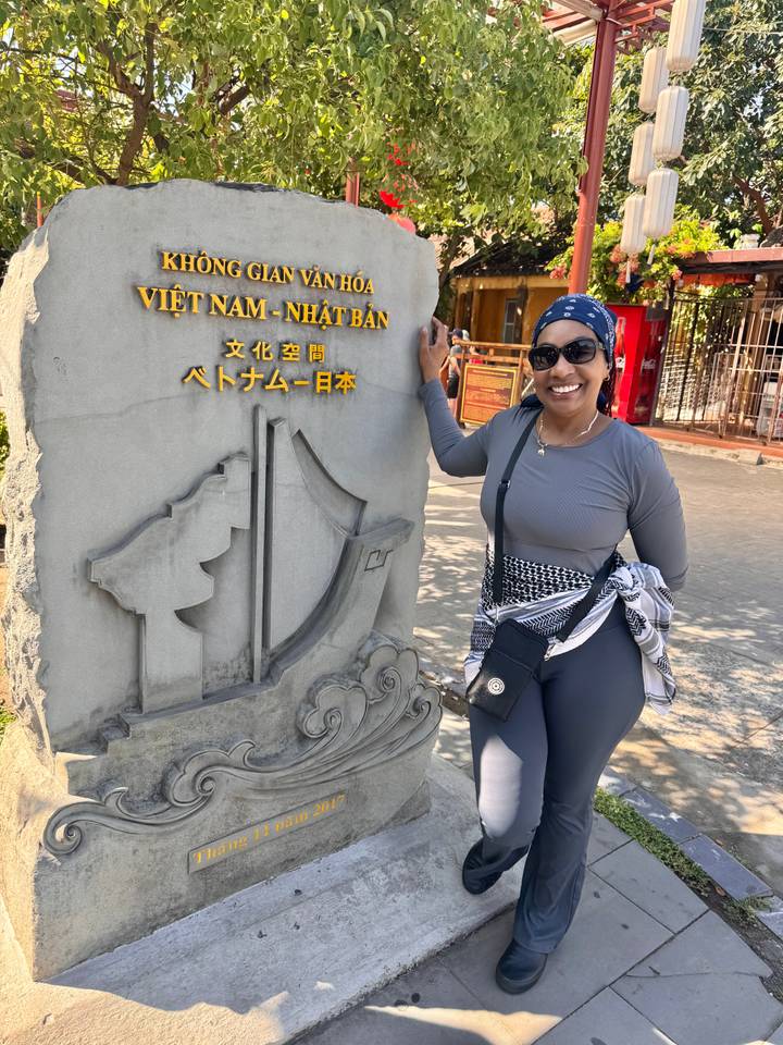 Traveller smiles beside a carved stone marker at Hoi An’s Japanese culture space.