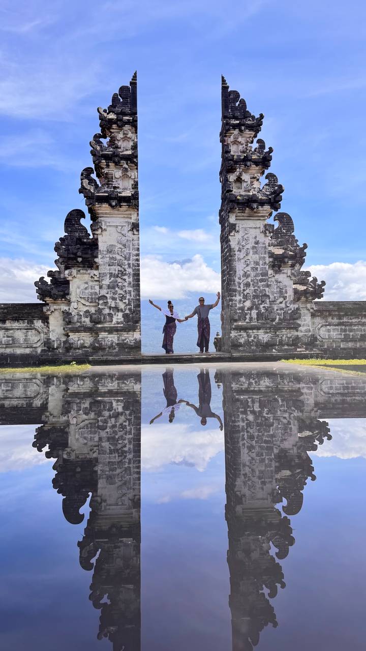 Couple framed by the Gates of Heaven with a mirror-reflection effect and mountains in the distance.