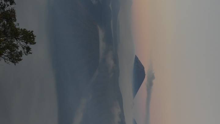 Volcanic peaks rise above layers of mist and low sunrise light creating a dreamy landscape