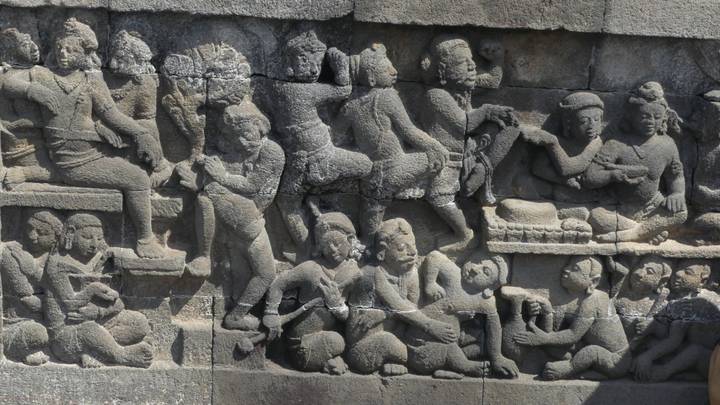 Intricate bas-relief carvings depicting ancient figures in stone panel at Borobudur