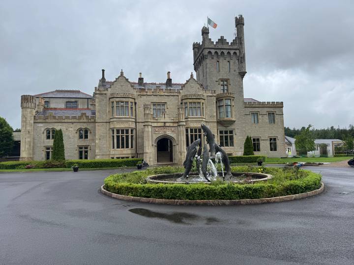 Grand manor-style castle hotel with fountain and dolphin statues on a grey, rainy Irish day.