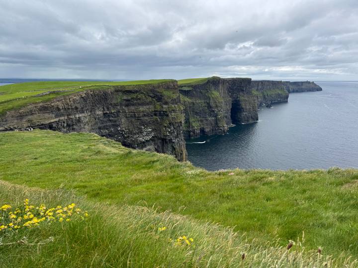 Dramatic sheer cliffs plunge into the Atlantic Ocean at the Cliffs of Moher under moody skies.