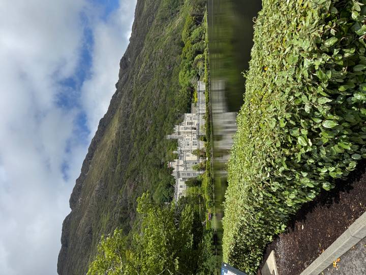 Kylemore Abbey reflected in a tranquil lake at the foot of a forested mountain in Connemara.