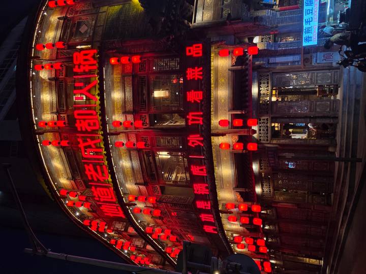 Night street view of a multi-storey restaurant lit by bright red Chinese characters and lanterns.