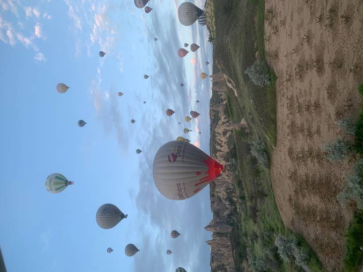 Numerous hot-air balloons of varying colors rise over Cappadocia’s spired landscape.