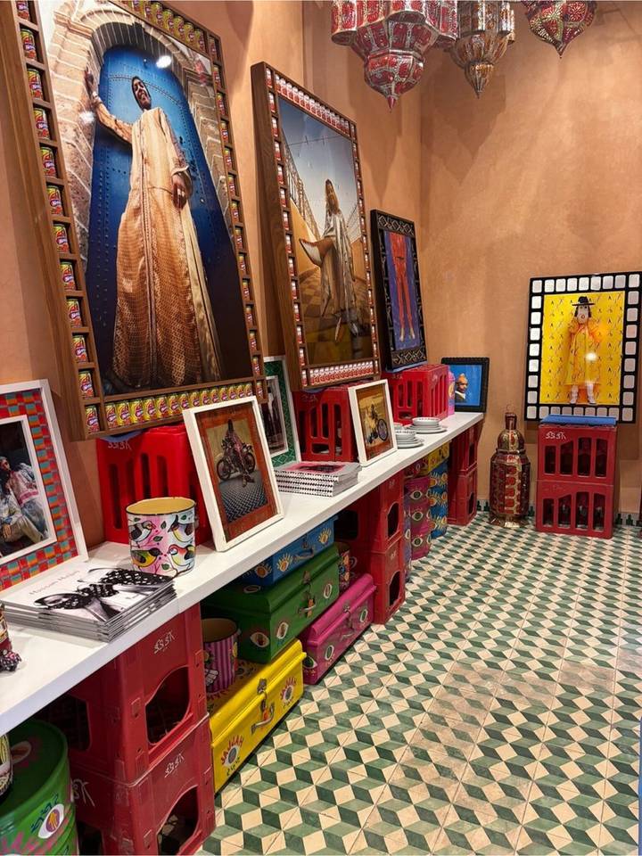 Colourful eclectic art pieces, photos and ceramics displayed on stacked crates inside a boutique shop.