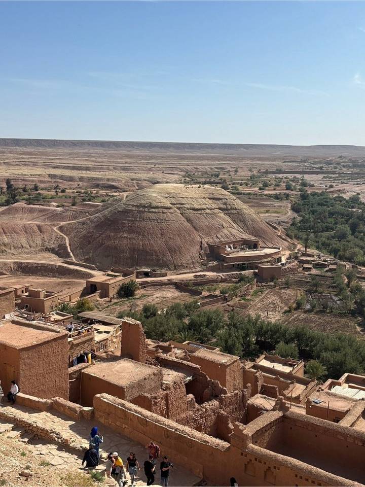 Arid hill and fertile valley seen from above with scattered traditional buildings in the foreground.