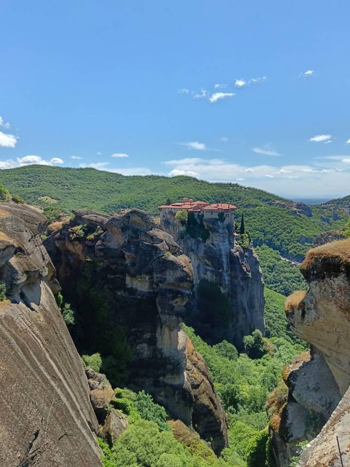 Iconic cliff-top monastery of Meteora perched high above green valley.