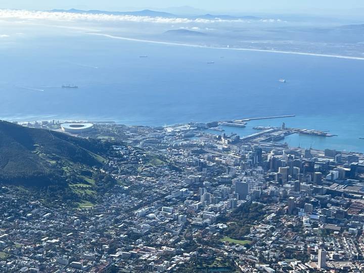 Aerial view of Cape Town with Lion's Head, the stadium and the city sprawling along the coastline under bright blue skies