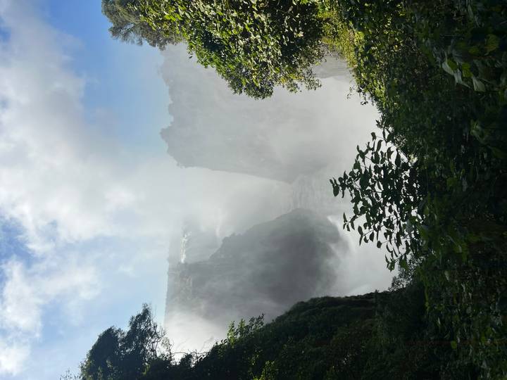 Mist-shrouded Victoria Falls cascading into a deep gorge surrounded by lush greenery