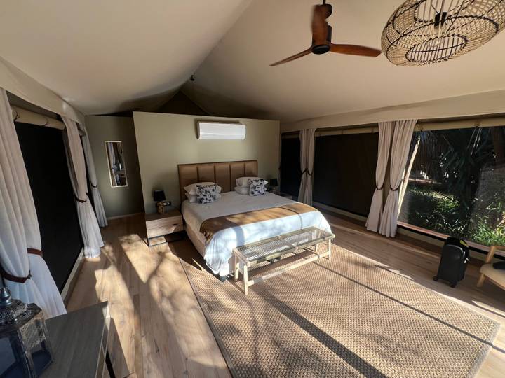 Spacious luxury tented suite with king bed, natural wood flooring and sunlight streaming through canvas windows