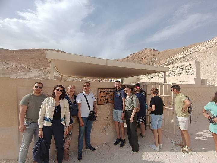 Tour group stands at the entrance sign of Tutankhamun’s tomb in the Valley of the Kings.
