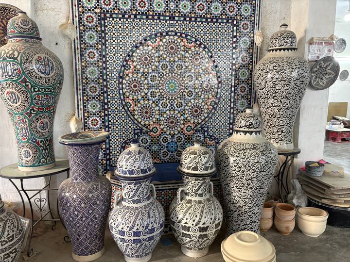 Display of intricately patterned Moroccan pottery vases against a colorful tiled backdrop.