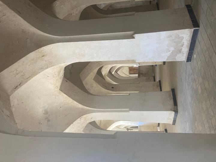 Vaulted white plaster arches inside an ancient madrasa or mosque hall.