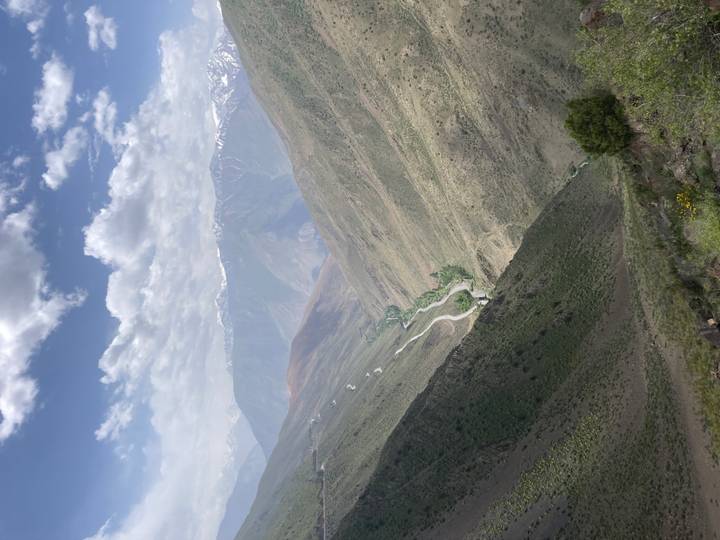 Expansive view down a rugged valley with winding river and distant snow mountains.