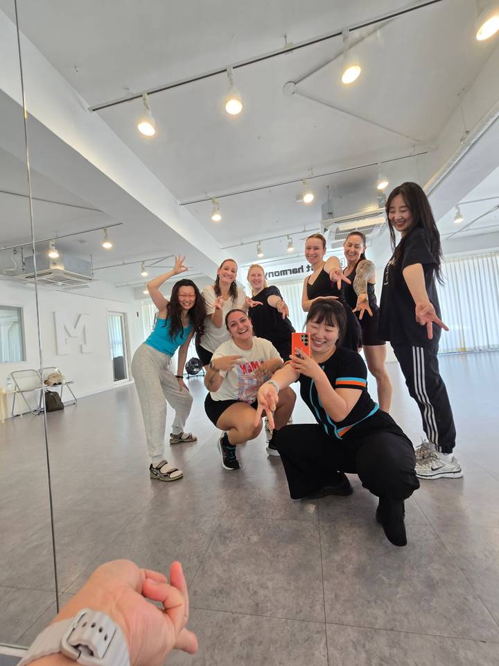 Dance class participants strike playful poses in a mirrored studio.