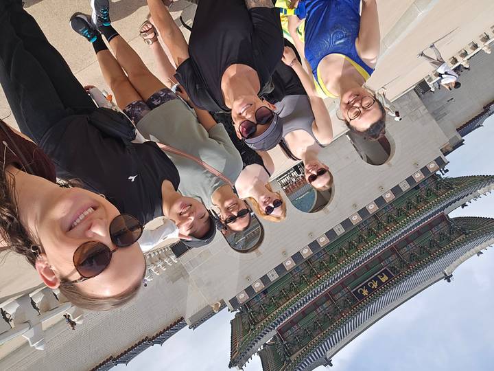 Group selfie in front of Gwanghwamun Gate at Gyeongbokgung Palace on a bright day.