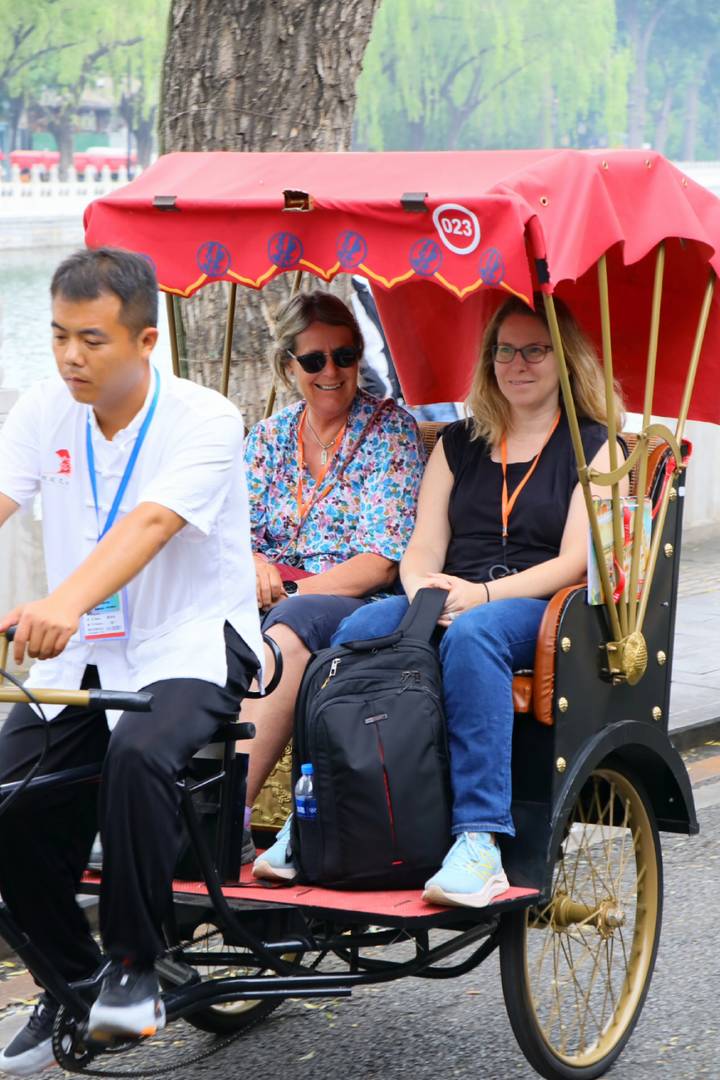 Travelers riding in a cycle rickshaw driven by a local rider through Beijing’s hutongs.