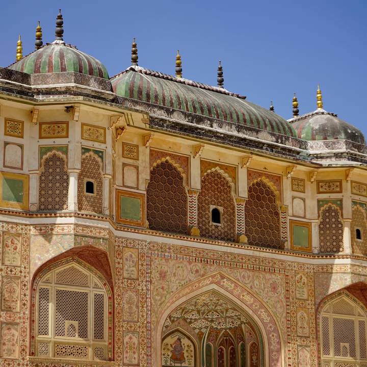 Colorful and intricately painted façade of Amber Fort with detailed arches and patterns.