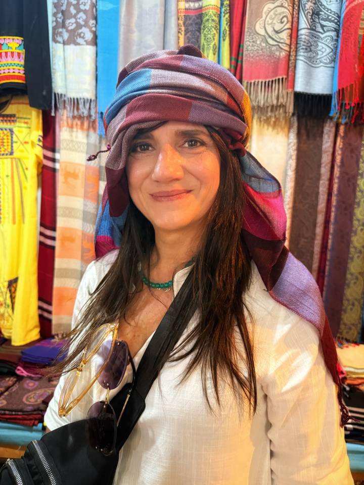 Portrait of smiling woman wearing a colorful scarf and beaded necklace in market setting