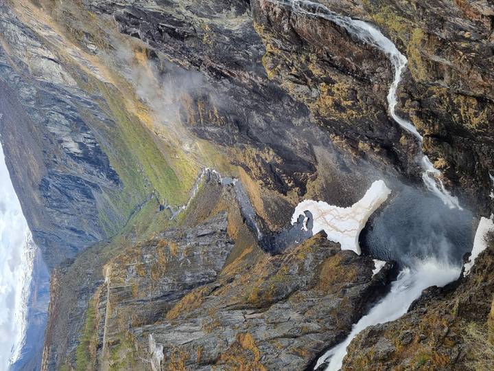 Dramatic canyon with a tall waterfall plunging into a misty pool far below.