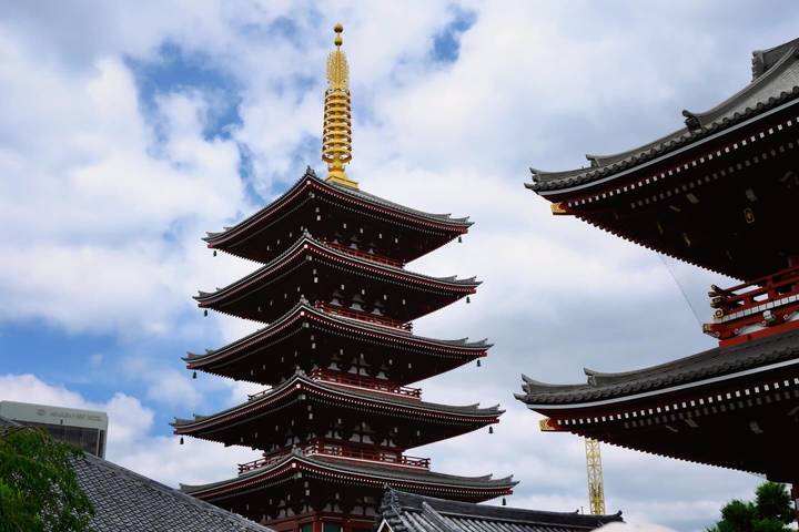 Multi-tiered pagoda with golden finial set against a blue sky with scattered clouds