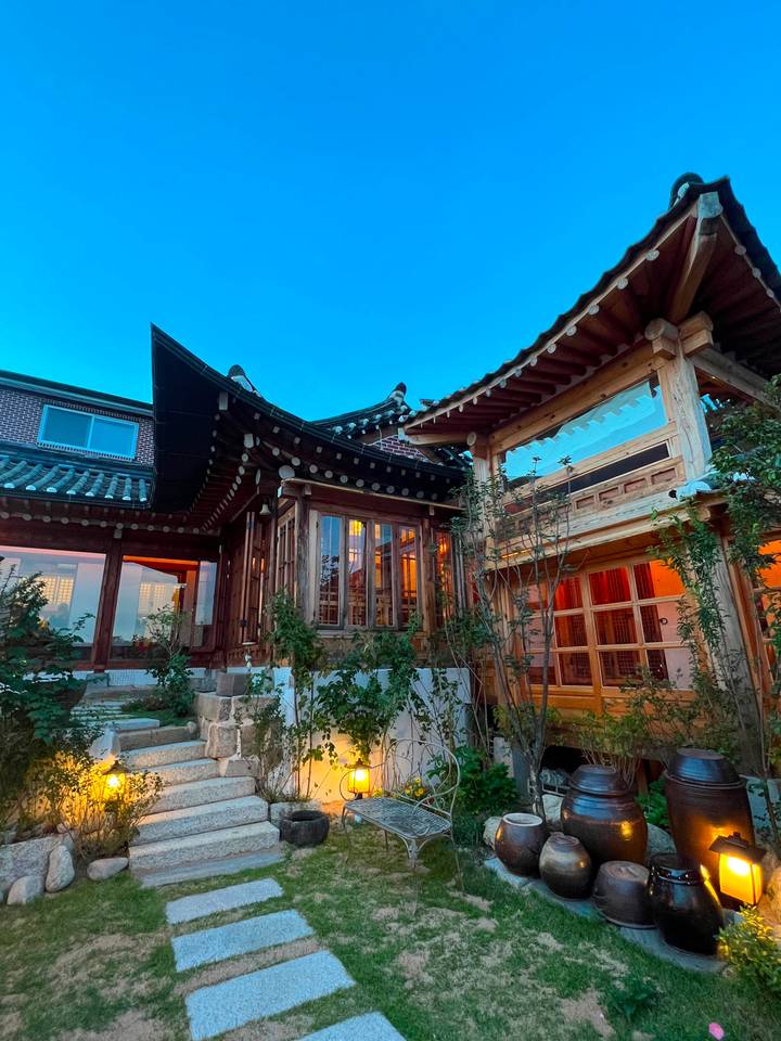 Traditional Korean hanok house with wooden lattice windows lit warmly at dusk