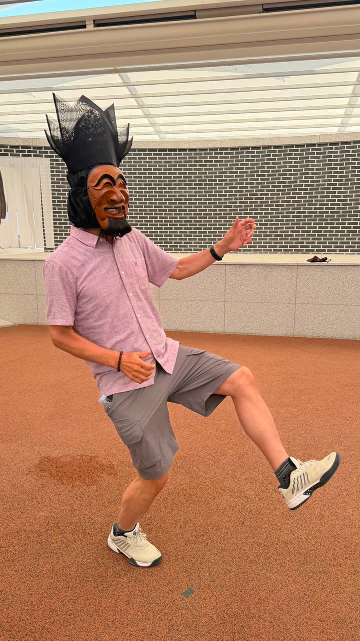 Young man playfully posing mid-step on an outdoor sports surface