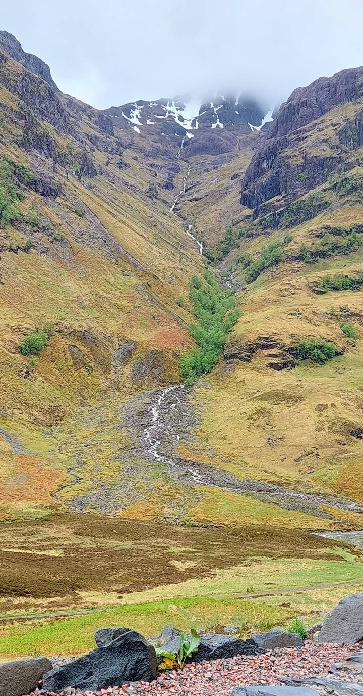 A remote Scottish glen with a small winding stream and mossy, brown and green hillsides.