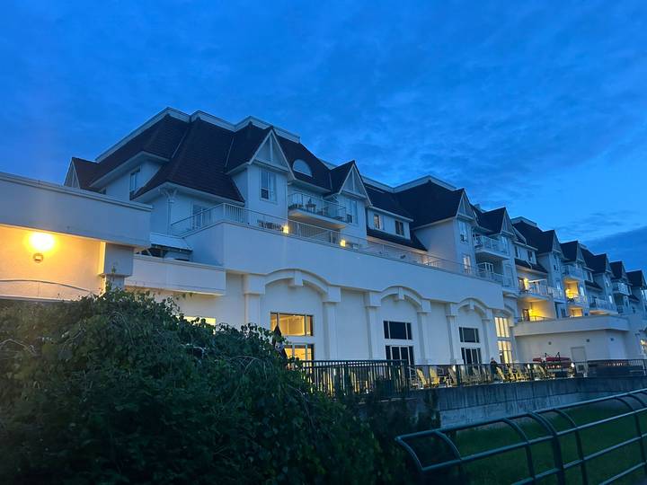 A modern hotel building illuminated at dusk beneath a deep blue evening sky.